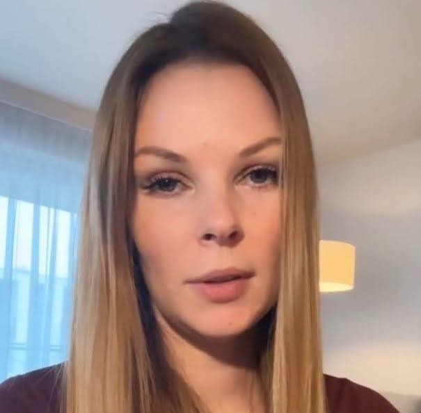 Małgorzata Tomaszewska w dynamicznej pozie na planie programu telewizyjnego, w eleganckim stroju, z uśmiechem i gestykulacją.