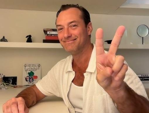Jude Law odbierający nagrodę BAFTA na uroczystej ceremonii, z dumą trzymający statuetkę.