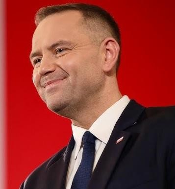 Karol Nawrocki, prezes IPN, podczas wystąpienia publicznego, z dynamicznym oświetleniem podkreślającym jego zaangażowanie.