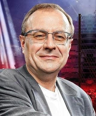 Antoni Dudek podczas wykładu lub debaty, gestykulujący, co podkreśla jego zaangażowanie i rolę publicznego intelektualisty.