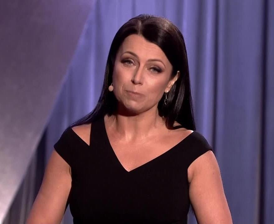 Adrianna Borek w roli Krystyny, gosposi księdza Janusza, podczas występu Kabaretu Nowaki na scenie, w dynamicznej pozie oddającej humor i energię jej kreacji.