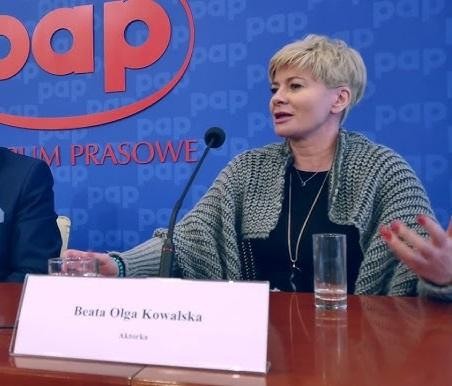 Beata Olga Kowalska w studiu nagraniowym, w słuchawkach, z mikrofonem, skupiona na pracy dubbingowej.