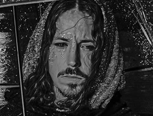 Michał Szpak w zbliżeniu, z intensywnym spojrzeniem, w dramatycznym makijażu i ekstrawaganckim stroju scenicznym, z jego charakterystycznymi długimi włosami.